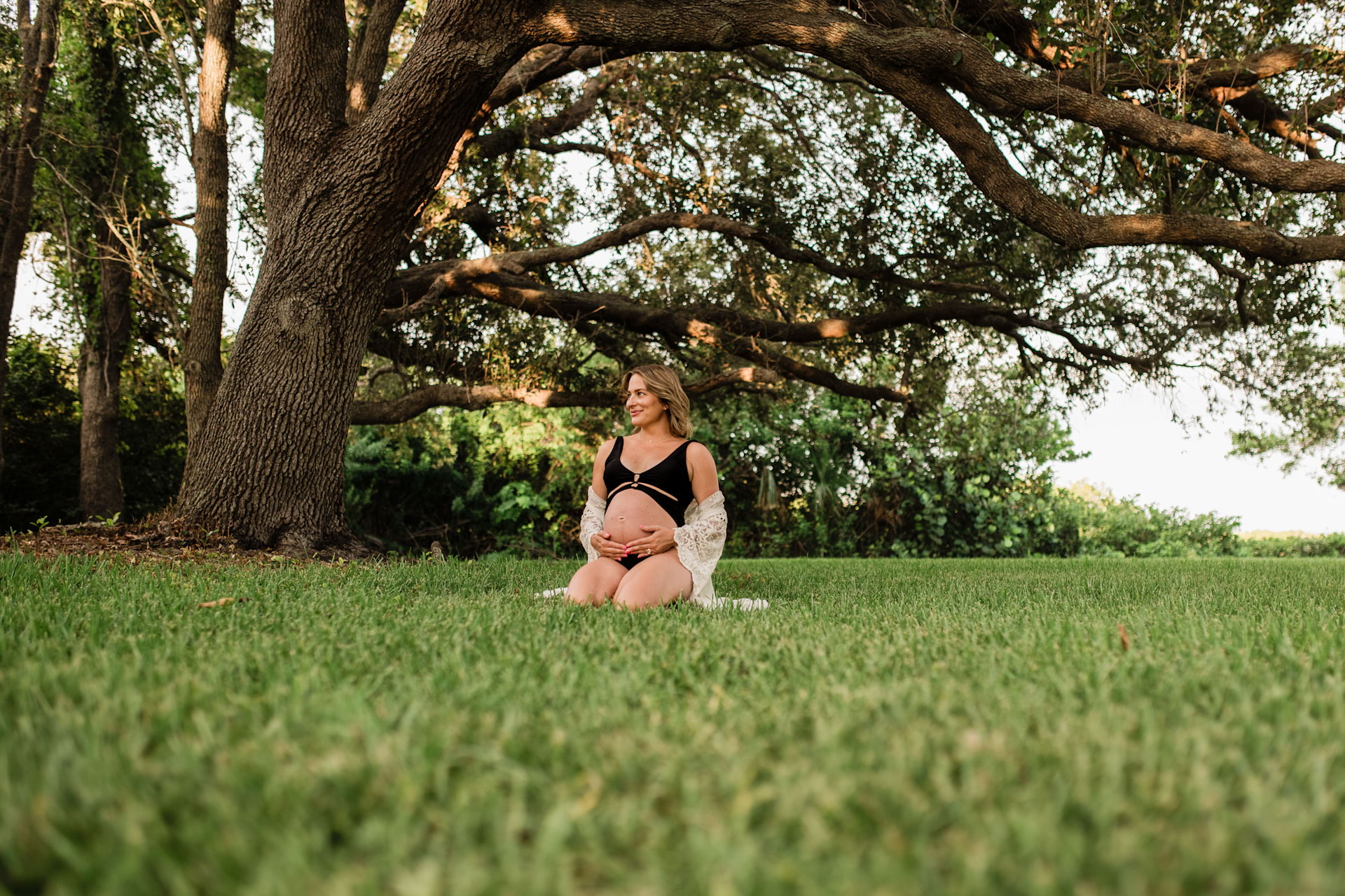 Photo of a sitting pregnant woman on a grassy meadow